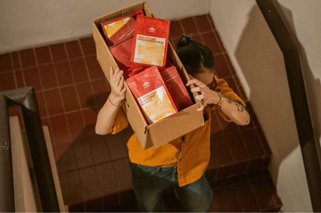 Femme transportant une boite avec des produits de l'epicerie.